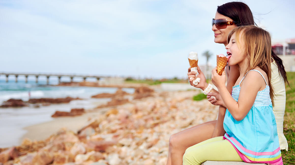 A couple in an open-top convertible parked near beach watching the sunset