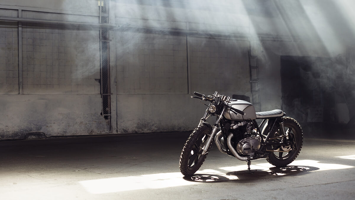 A parked motorcyle on serene highway and open fields