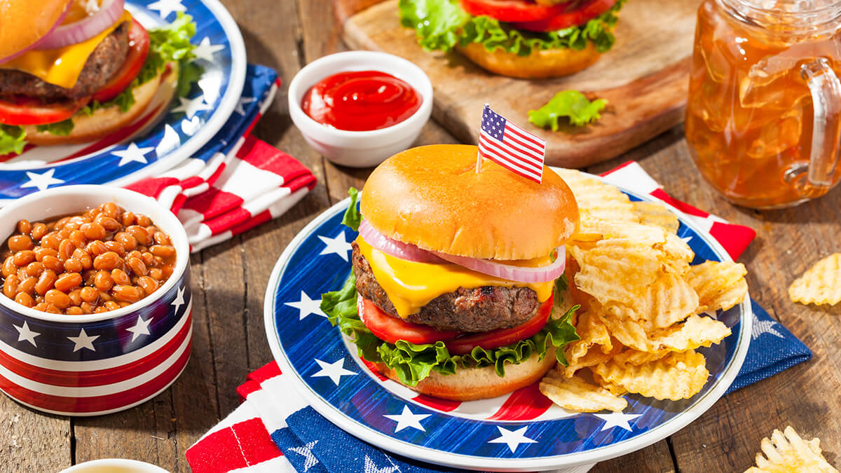 A picnic table with yummy burgers ready to eat
