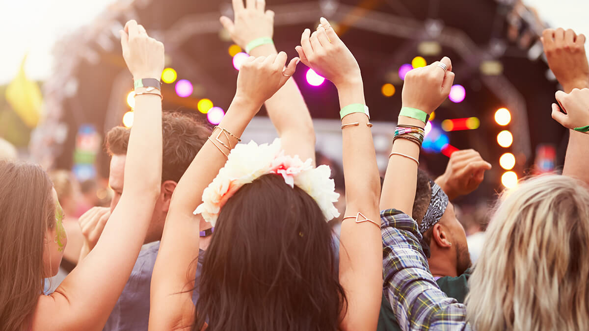A concert attendee making a heart sign with hands overhead 