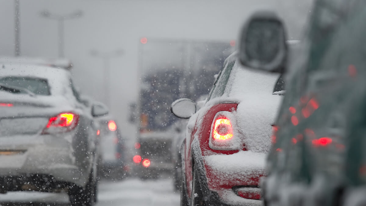 A car with bright headlights driving on a dark snowy highway