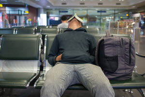 Staying sane when stuck at the airport Man sleeping in an airport terminal with a book on his face