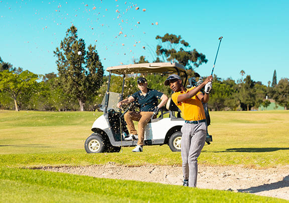A golfer hitting ball out of sand trap