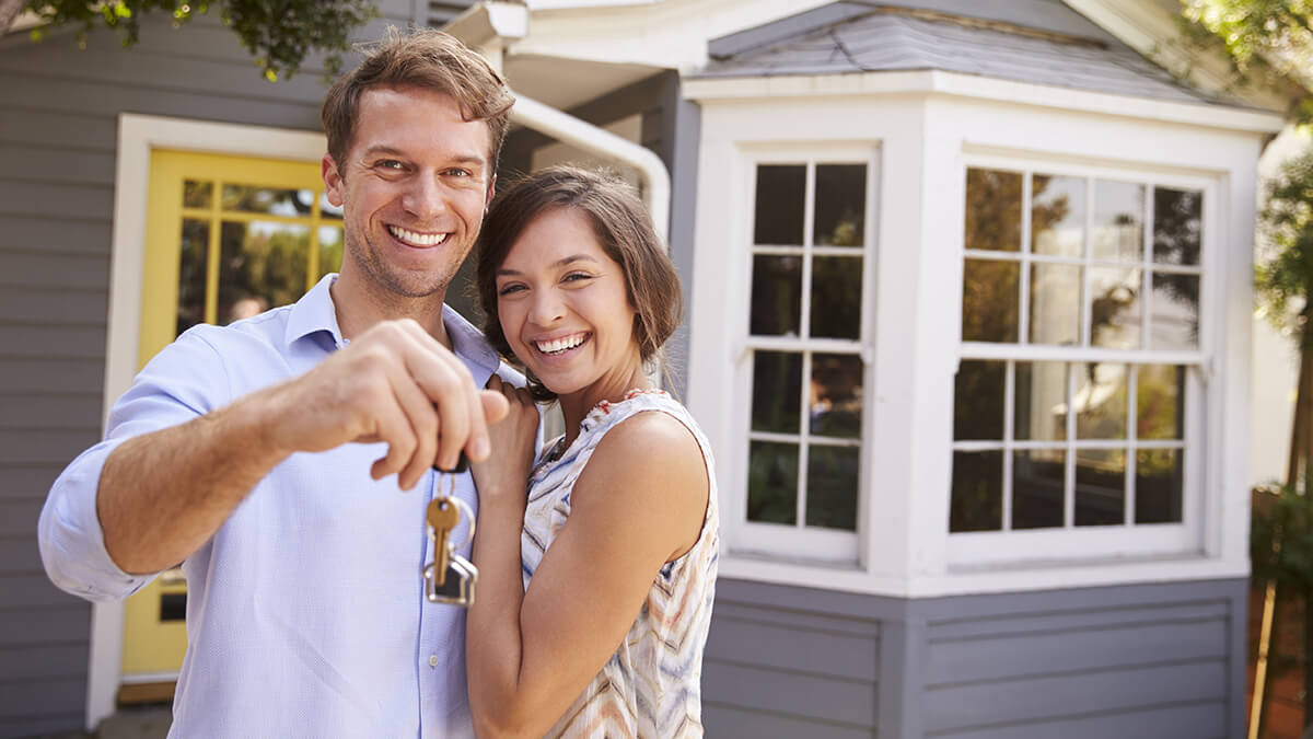 A bird's eye view of a couple laying on their backs on the floor dreaming of homeownership