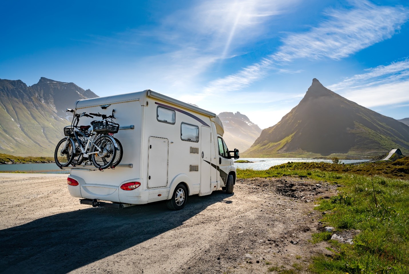 RV parked infront of a river with mountains behind.