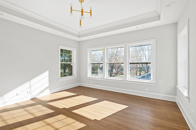 Modern and Neutral Bedroom. Vacant room with hardwood floors, gold chandelier, and window for virtual staging.